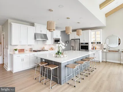 a kitchen with stainless steel appliances kitchen island granite countertop a sink dishwasher a stove a dining table and chairs with wooden floor