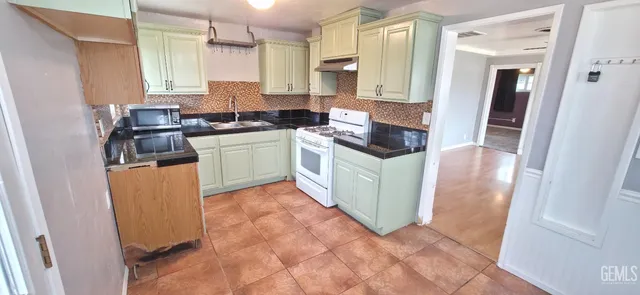 a kitchen with granite countertop a sink stove and refrigerator