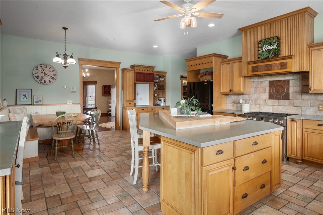 9419 Robinson Road Chardon, OH 44024 - Photo 5 of 46 Kitchen with a center island, light countertops, stainless steel range with gas stovetop, freestanding refrigerator, and hanging lights