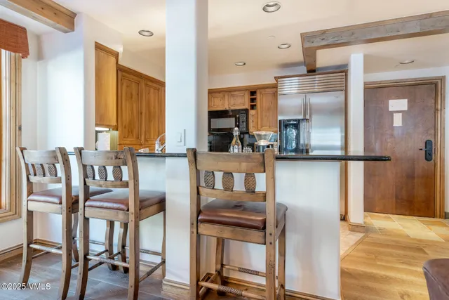 a kitchen with stainless steel appliances refrigerator dining table and chairs
