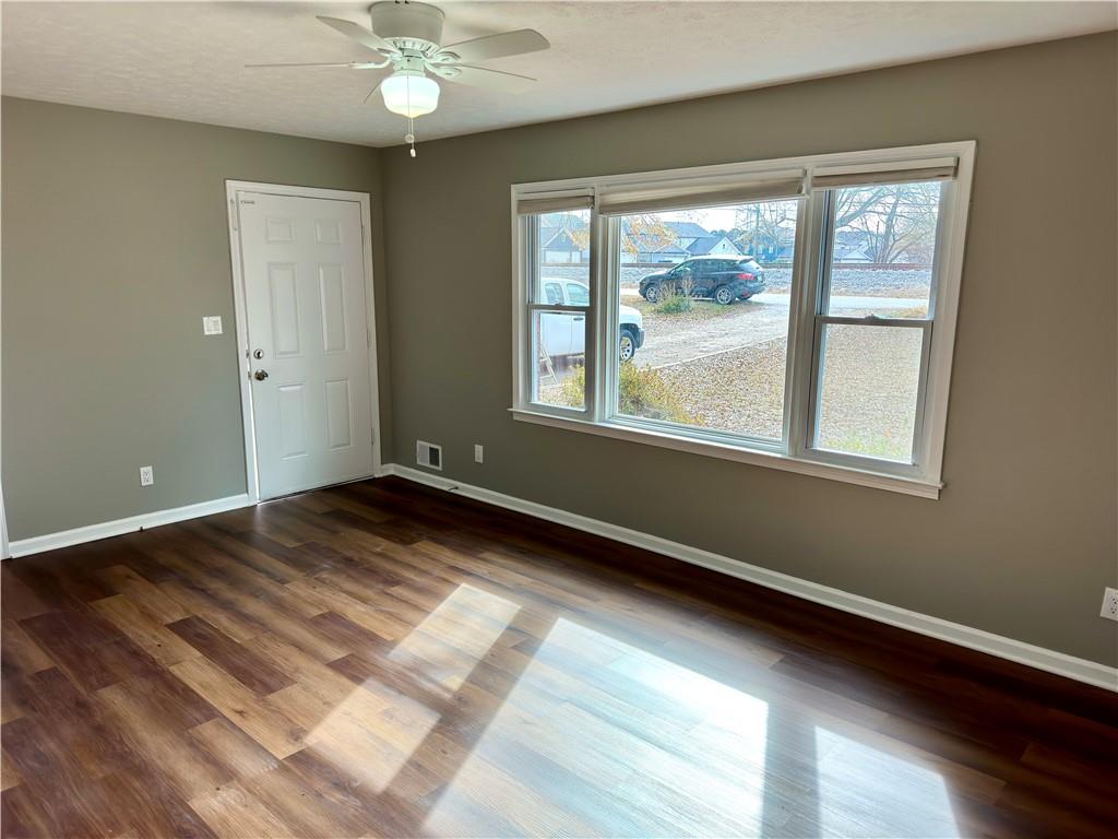 Unfurnished room featuring dark hardwood / wood-style flooring, a healthy amount of sunlight, and ceiling fan