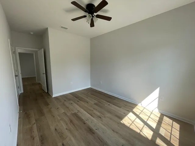 a view of an empty room with window and wooden floor