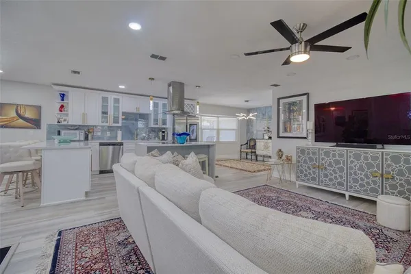a living room with stainless steel appliances furniture and a flat screen tv