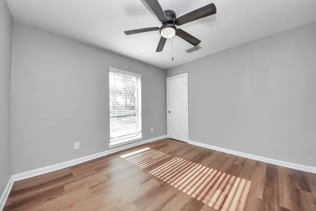 an empty room with wooden floor and windows