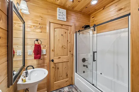 a bathroom with a tub shower sink and mirror