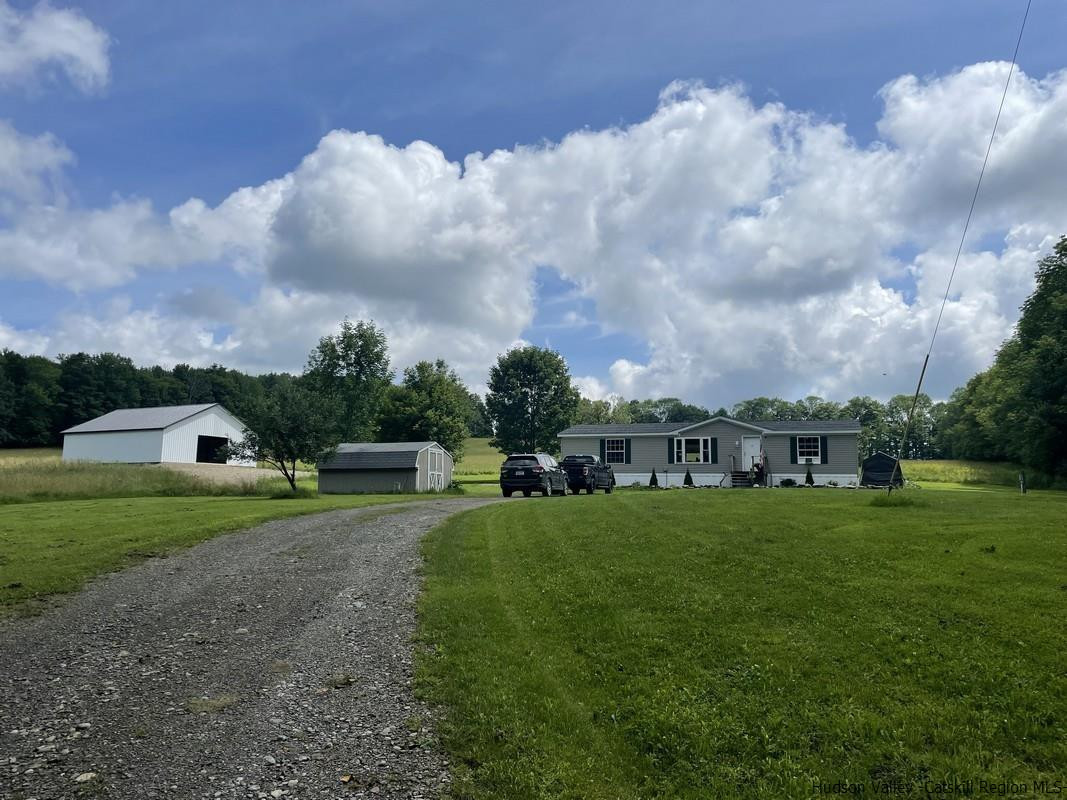 302 Springfield Hill Road Cooperstown, NY 13326 - Photo 1 of 19 a view of a big yard with a house in the background
