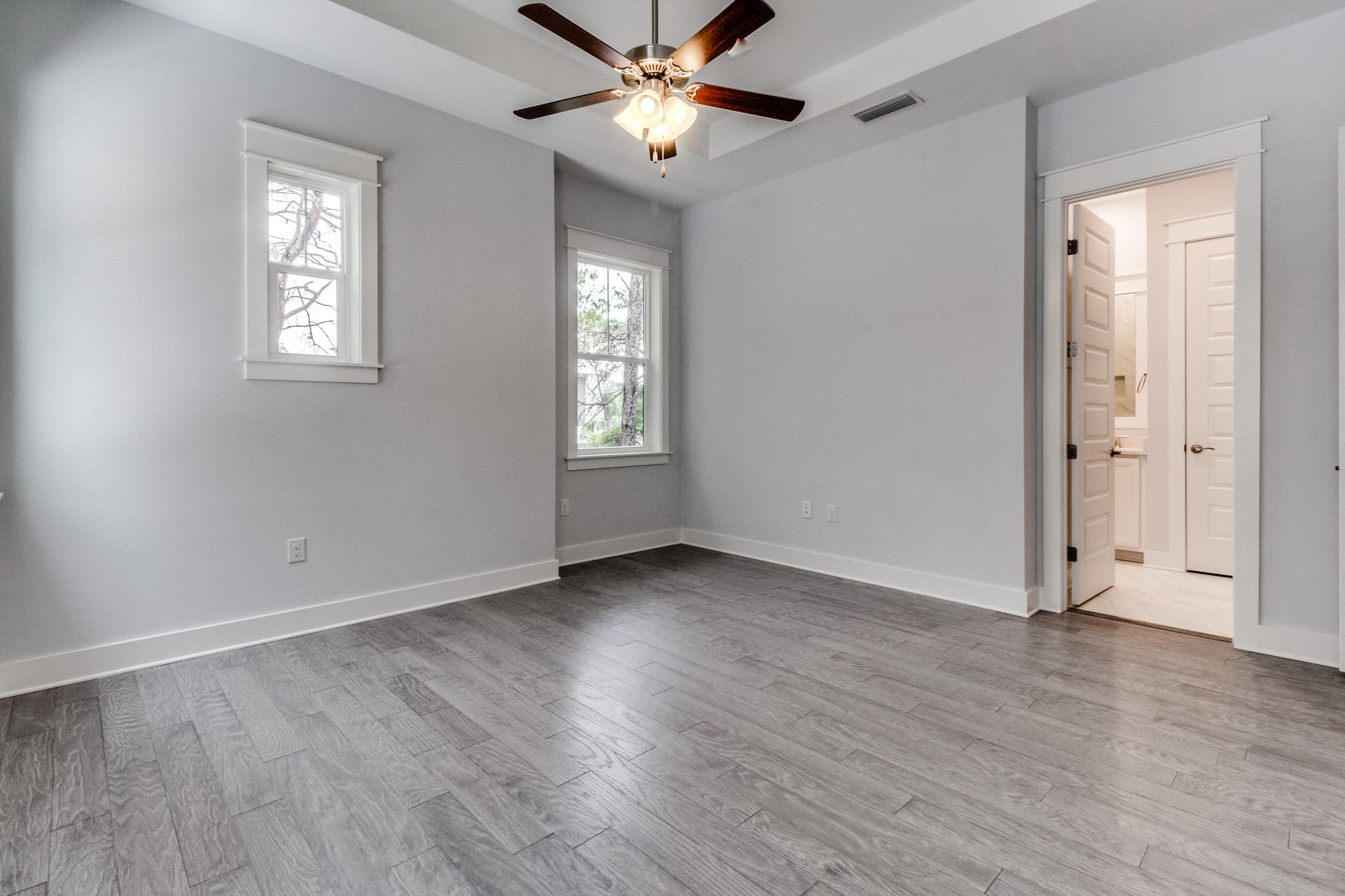 146 Pine Lands Loop Inlet Beach East, Unit A Inlet Beach, FL 32461 - Photo 36 of 42 an empty room with wooden floor ceiling fan and windows