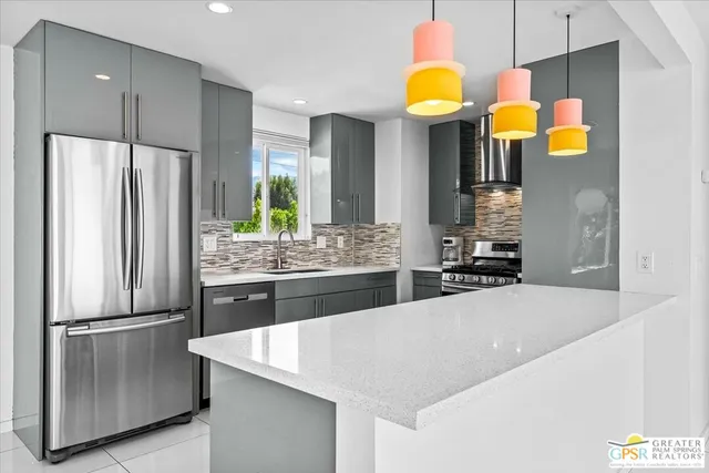 a kitchen with stainless steel appliances kitchen island granite countertop a refrigerator a stove and a sink