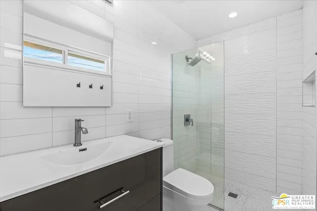 a bathroom with a sink a toilet a glass door shower and mirror