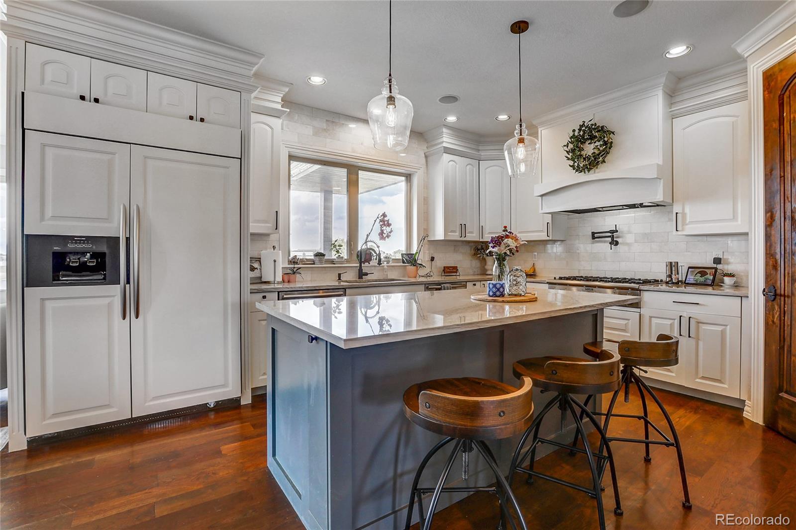 147 Commander Drive Erie, CO 80516 - Photo 4 of 50 a kitchen with stainless steel appliances granite countertop a sink a stove a refrigerator and island with wooden floor