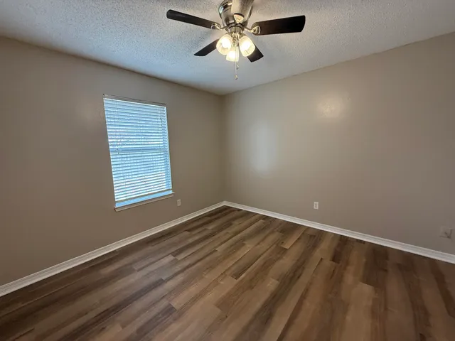 a view of an empty room with window and chandelier fan