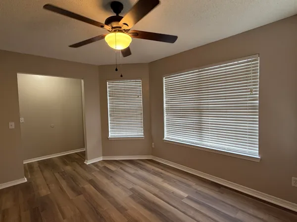 a view of an empty room with window and chandelier fan