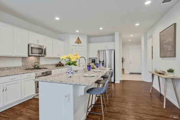 a kitchen with kitchen island granite countertop a sink stainless steel appliances and living room view