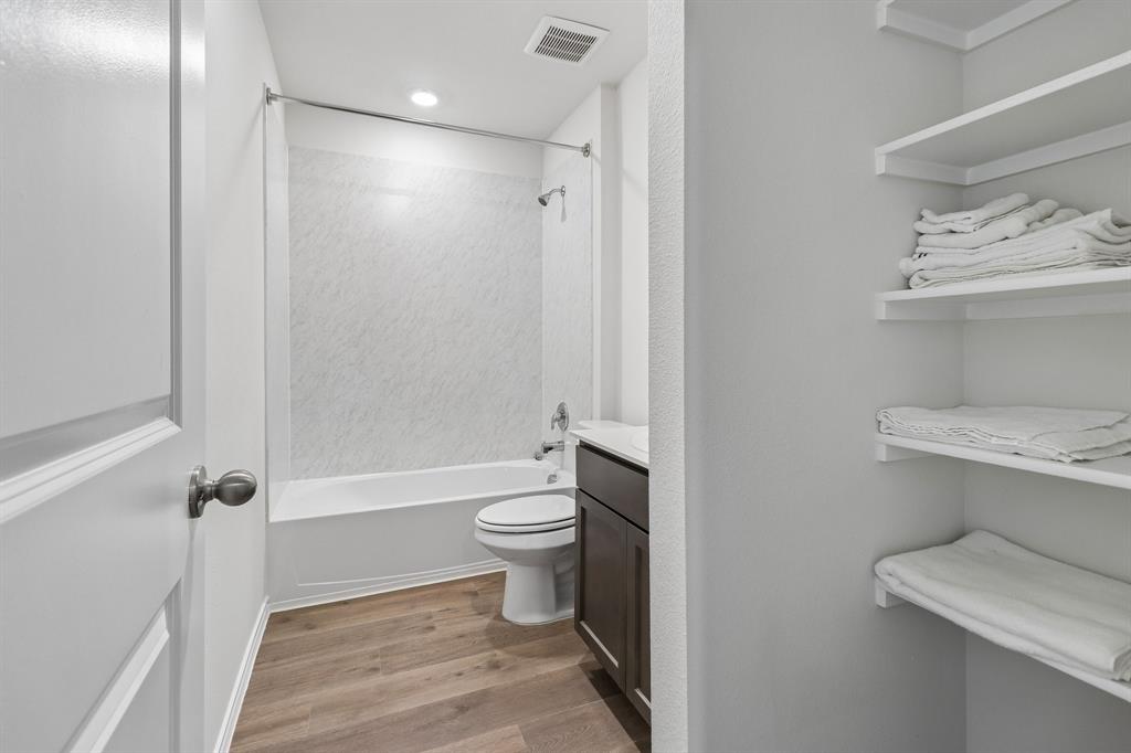 1453 Millstead Rill Road Caddo Mills, TX 75135 - Photo 18 of 40 Bathroom featuring wood-finish flooring, a white bathtub, a single vanity with a dark wood cabinet and white countertop, and built-in shelving
