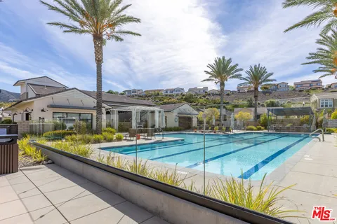 a view of a white house with a swimming pool and sitting area