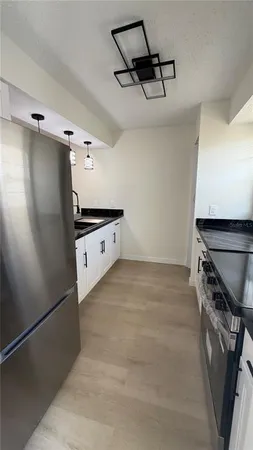 a kitchen with stainless steel appliances granite countertop a sink a stove and refrigerator