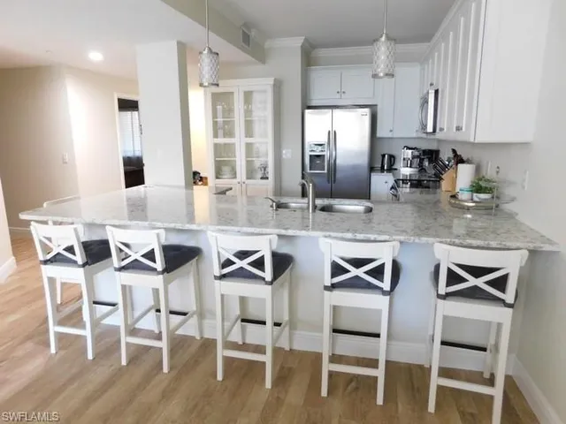 a kitchen with stainless steel appliances granite countertop a dining table chairs and granite counter tops