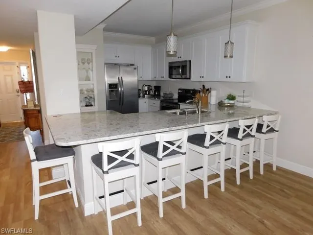 a kitchen with stainless steel appliances granite countertop a dining table chairs and granite counter tops