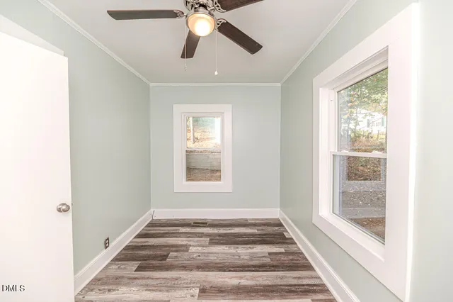 a view of an empty room with a window and wooden floor