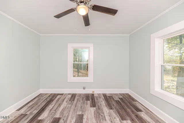 a view of empty room with wooden floor and fan