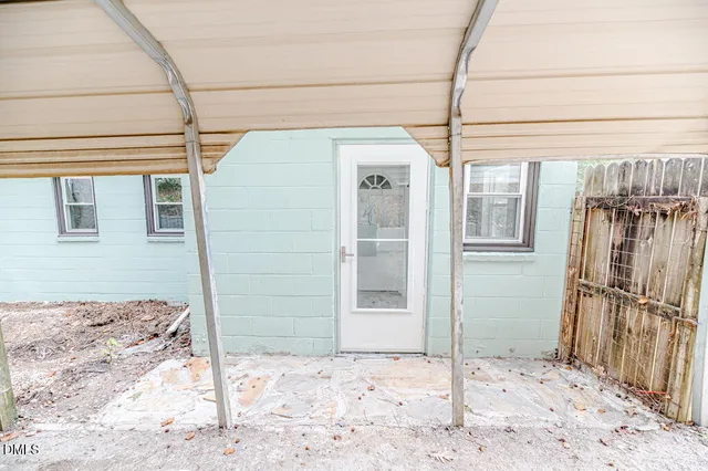 a backyard of a house with large tree and wooden fence