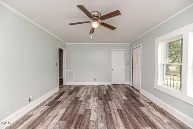 a view of empty room with wooden floor and fan