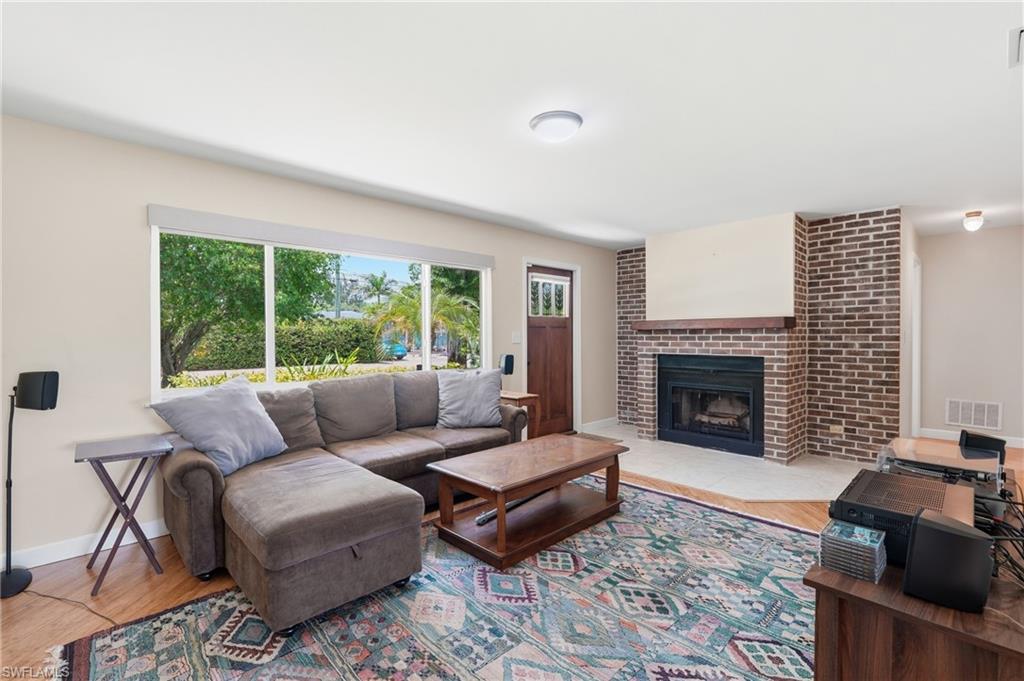 1316 Rordon Avenue Naples, FL 34103 - Photo 10 of 38 Living area featuring wood-finish flooring, a brick fireplace with a wood mantel, and a large window