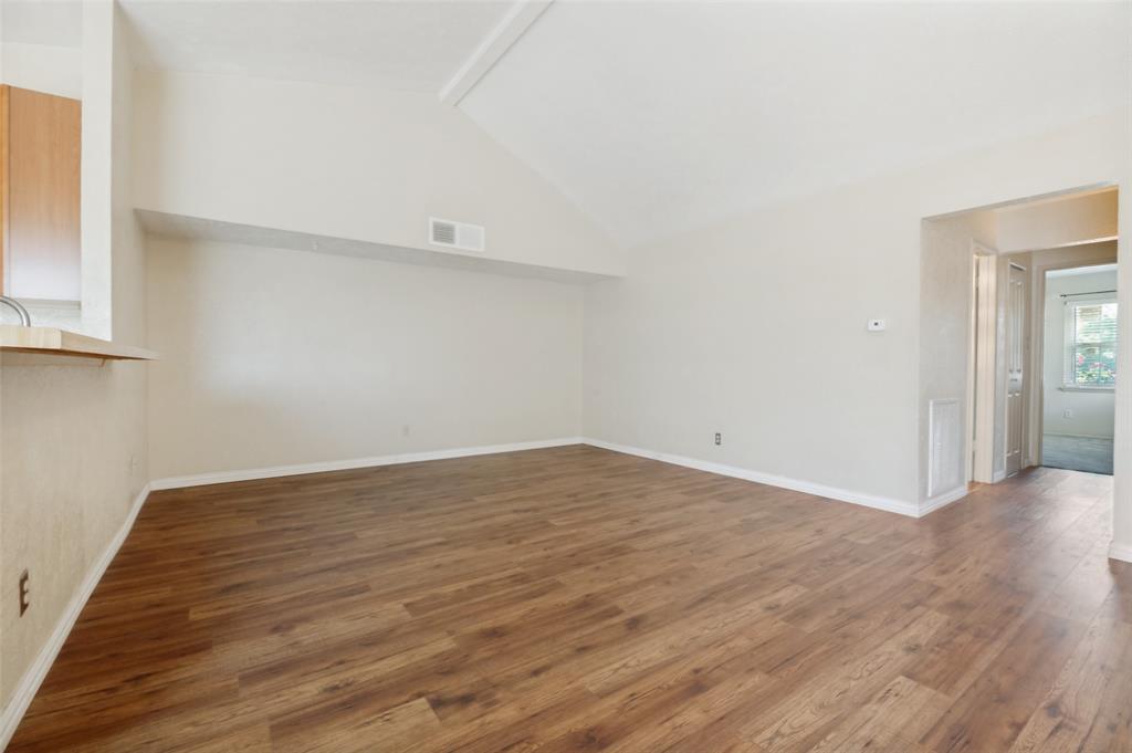 7305 Pineberry Road Dallas, TX 75249 - Photo 4 of 25 a view of an empty room with wooden floor and a window