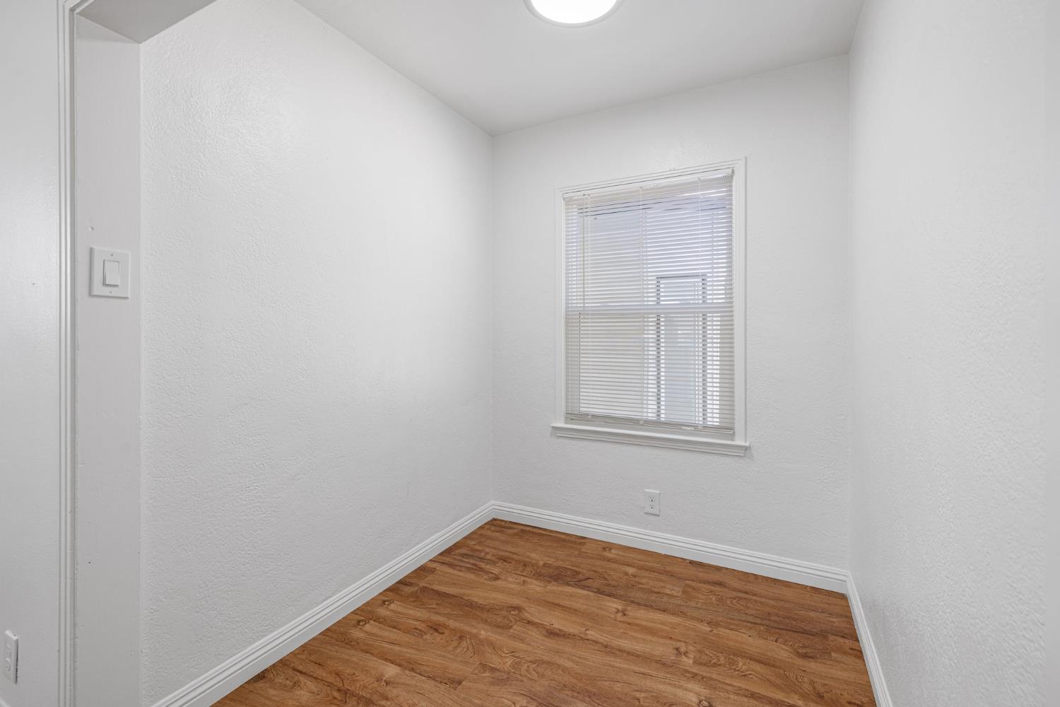 210 East Bush Street Lemoore, CA 93245 - Photo 14 of 42 a view of an empty room with wooden floor and a window