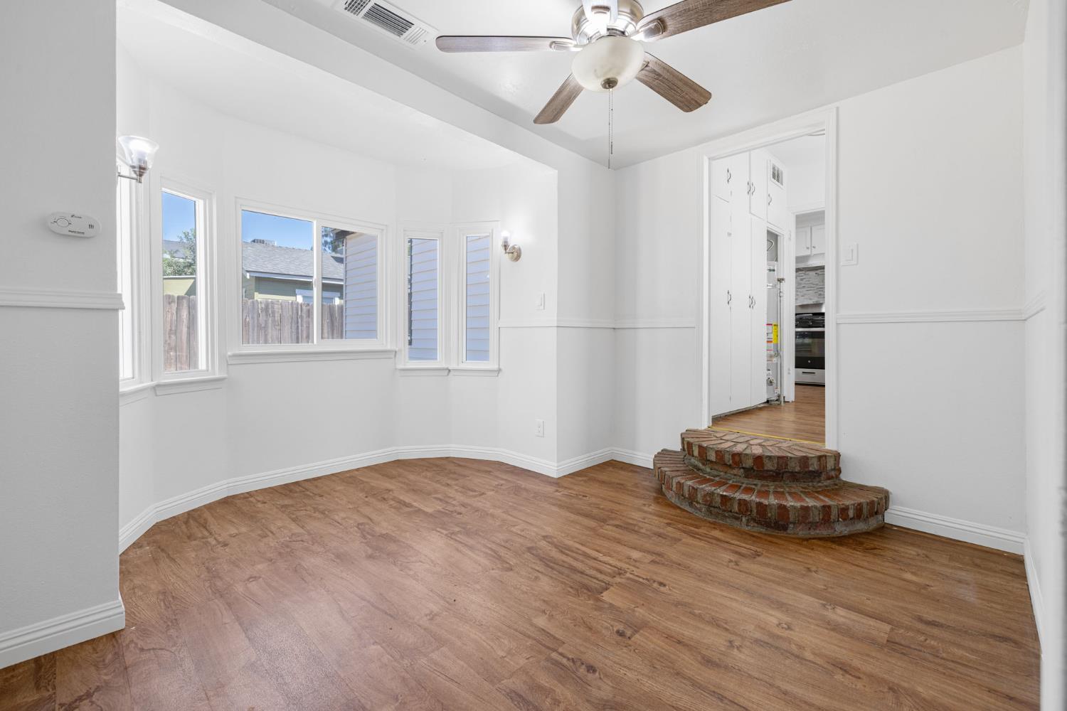 210 East Bush Street Lemoore, CA 93245 - Photo 19 of 42 a view of a livingroom with wooden floor and a ceiling fan