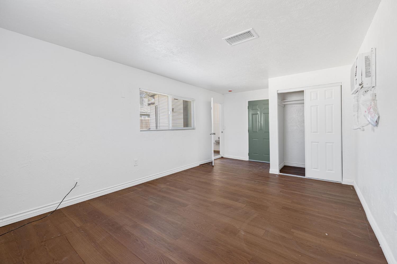 210 East Bush Street Lemoore, CA 93245 - Photo 23 of 42 a view of an empty room with wooden floor and a window