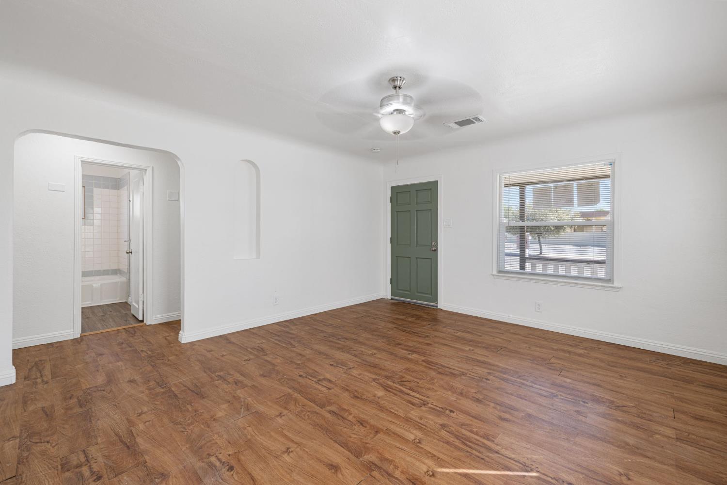 210 East Bush Street Lemoore, CA 93245 - Photo 7 of 42 a view of an empty room with wooden floor and a window
