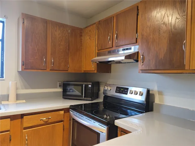a kitchen with granite countertop cabinets stove top oven and microwave