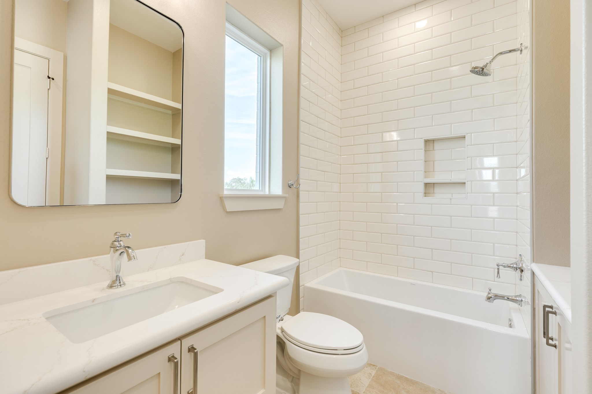 1737 Flintlock Court Angleton, TX 77515 - Photo 37 of 47 This bathroom features a clean, modern design with white subway tile in the shower, a built-in shelf, and a sleek vanity with a marble countertop. Natural light streams through the window, enhancing the bright, airy feel.