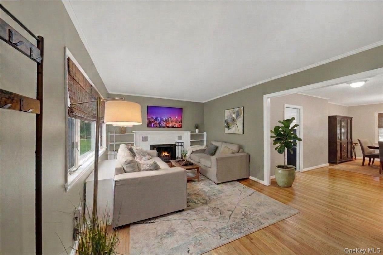 10 Susquehanna Road Ossining, NY 10562 - Photo 2 of 31 Living area featuring wood-finish flooring, a fireplace with a mantel, built-in shelving, and crown molding