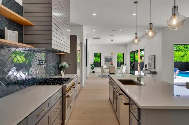 a kitchen with kitchen island stainless steel appliances a sink a counter top space a stove and cabinets