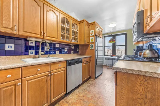 a kitchen with stainless steel appliances granite countertop a refrigerator a stove and a sink with cabinets