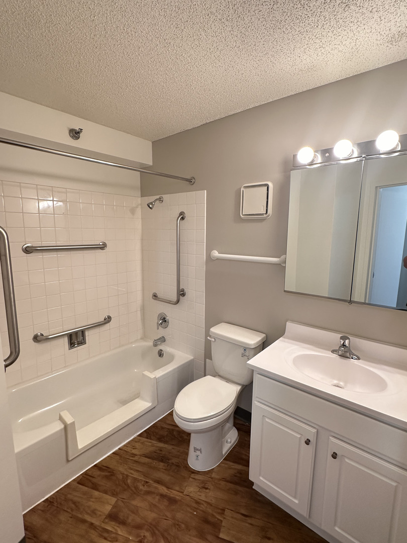 8975 West Golf Road, Unit 625 Niles, IL 60714 - Photo 5 of 6 a bathroom with a toilet a sink a mirror a bathtub and vanity