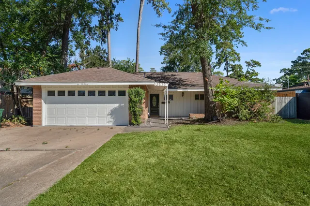a view of a house with a yard potted plants and large tree