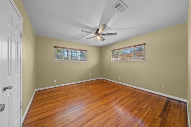a view of an empty room with a window and a chandelier fan
