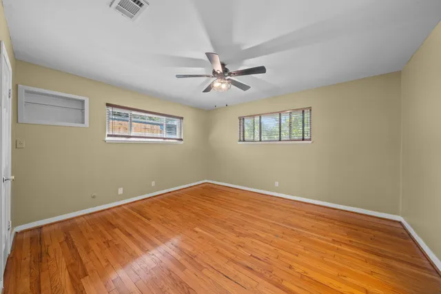 a view of an empty room with a window and a chandelier fan