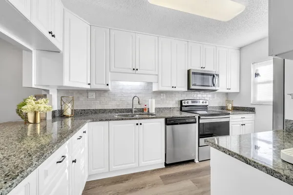 a kitchen with stainless steel appliances granite countertop a sink stove and refrigerator