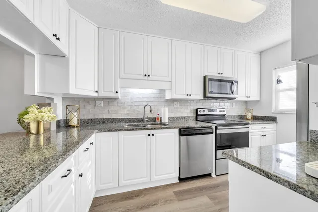 a kitchen with stainless steel appliances granite countertop a sink stove and refrigerator