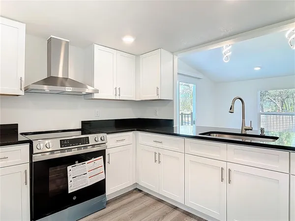 a kitchen with granite countertop white cabinets and a stove