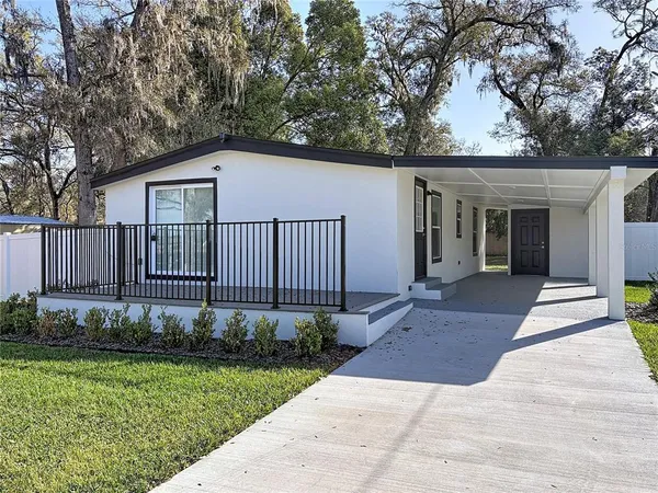 a view of a house with a yard and large tree