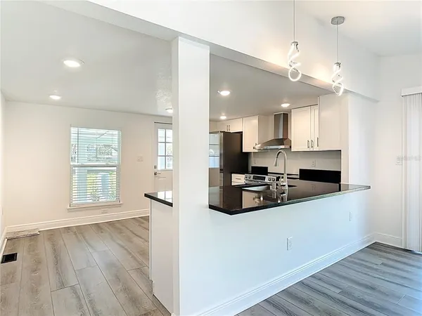 a large kitchen with stainless steel appliances a large counter top and a wooden floors