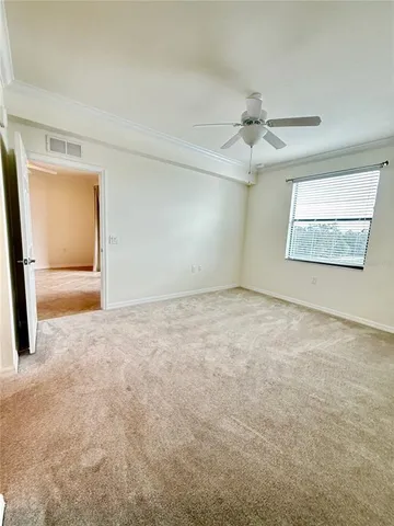 an empty room with windows and ceiling fan