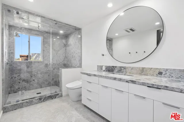 a bathroom with a granite countertop sink mirror and toilet