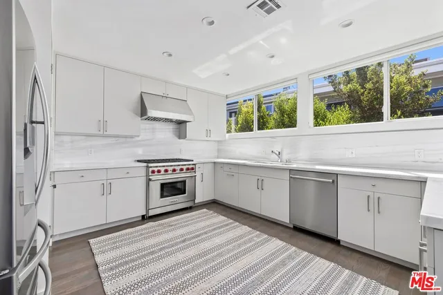 a kitchen with a stove white cabinets wooden floor and a sink