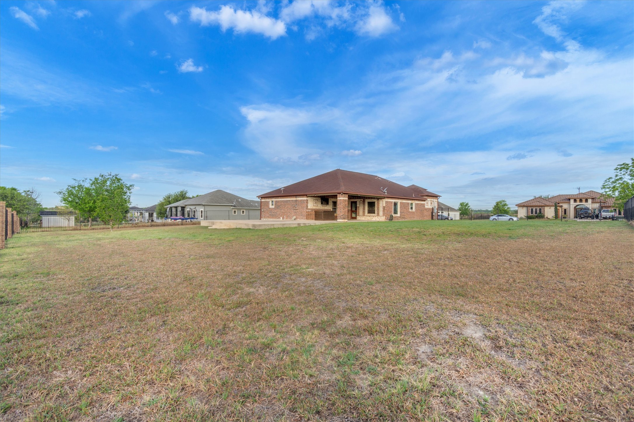 164 Peck Street Kyle, TX 78640 - Photo 19 of 19 Back of house with a yard, brick siding, and a patio